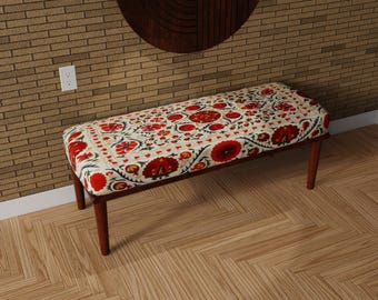 May include: A rectangular bench with a floral patterned cushion. The cushion features a cream background with red and orange floral designs. The bench has a dark brown wooden frame and legs. The bench is approximately 48 inches long.