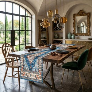 May include: A wooden dining table with a blue and red patterned table runner. The table is set with plates, cutlery, and a teapot. The room features large windows, decorative lighting, and a gold-framed mirror. The table runner is approximately 200 cm long.