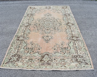May include: A vintage rug with a light pink background and a detailed floral pattern in shades of green and brown.