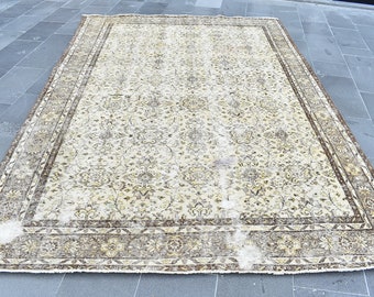 May include: A vintage cream-colored rug with a brown floral pattern and a brown border. The rug has a worn and faded look, giving it a rustic charm.
