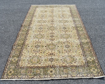 May include: A vintage rug with a cream background and a floral pattern in shades of green, brown, and pink. The rug has a border with a geometric design.