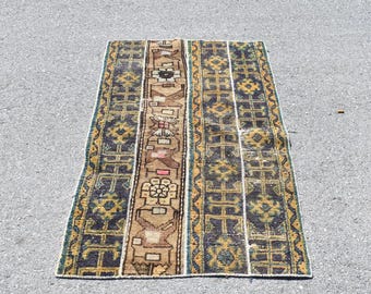 May include: A rectangular vintage rug with a central brown panel featuring floral and geometric patterns. The rug has dark blue and yellow accents, with a border of blue and green. The rug is likely made of wool and is suitable for a living room or bedroom.