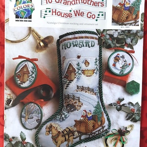 May include: A cross stitch kit package titled To Grandmothers House We Go featuring a Christmas stocking with a horse-drawn sleigh scene, the name Howard, and three circular ornaments. The design includes snowy landscapes, cabins, and trees.