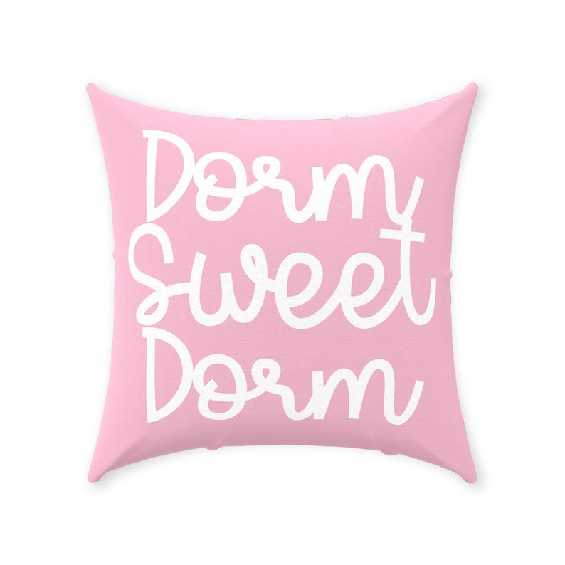 May include: A pink throw pillow with the text "Dorm Sweet Dorm" in white cursive lettering.