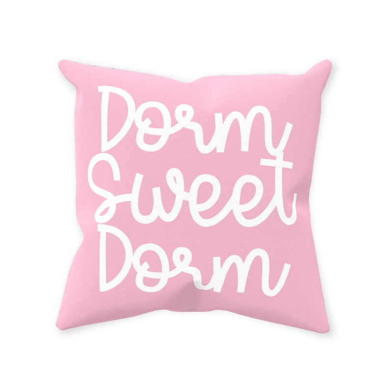 May include: A pink throw pillow with the text "Dorm Sweet Dorm" in white cursive lettering.