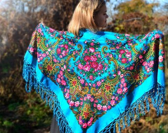 May include: A blue shawl with a floral pattern and fringe. The shawl is made of a soft, lightweight fabric and is perfect for adding a touch of elegance to any outfit.