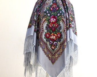 May include: A light blue shawl with a floral pattern and fringe. The shawl features a central design of red, yellow, and purple flowers with green leaves.