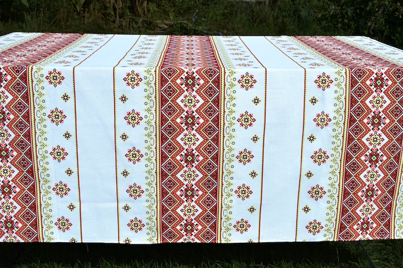 May include: White tablecloth with red, yellow, and green embroidered geometric patterns.