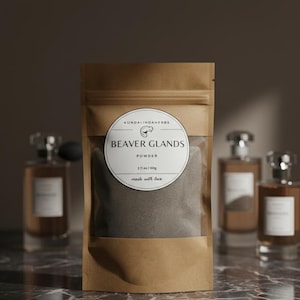 Könnte beinhalten: Ein brauner Papierbeutel mit einem transparenten Fenster, gefüllt mit einem grauen Pulver. Das Etikett lautet "BEAVER GLANDS POWDER" mit einem Gewicht von 60g. Die Worte "made with love" stehen ebenfalls auf dem Etikett. Parfümflaschen sind im Hintergrund.