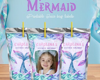 May include: Three silver juice pouch labels with a mermaid tail design, blue and purple watercolor waves, and a photo frame. The labels say "Carolina's Seventh Birthday".