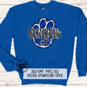 May include: A royal blue sweatshirt with a white and blue paw print graphic. The word "Cougar" is written in black script over the paw print.
