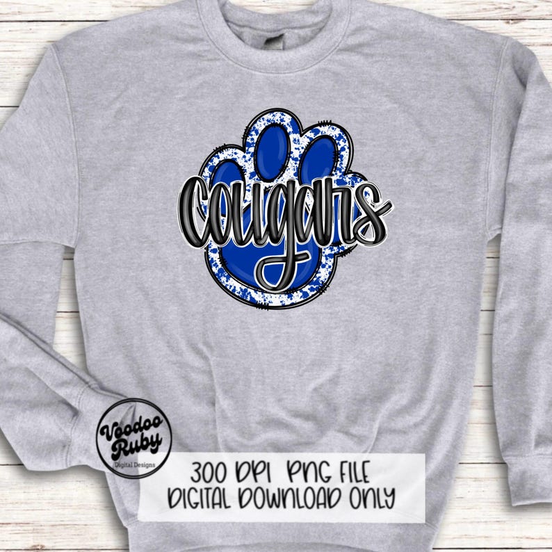 May include: A gray sweatshirt with a blue paw print graphic and the word "Cougar's" in black lettering. The paw print has a white splatter design.