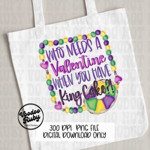 May include: A white tote bag featuring a graphic design with purple, green, and yellow Mardi Gras beads forming a rectangular frame. The text reads "WHO NEEDS A VALENTINE WHEN YOU HAVE KING CAKE?!" next to a colorful ring-shaped king cake.