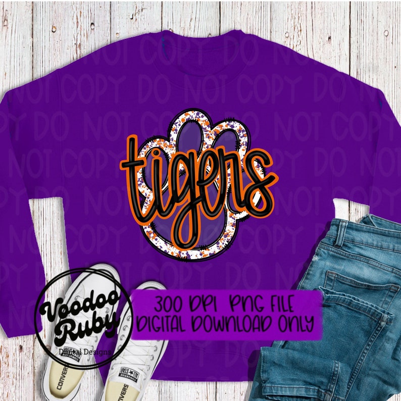 May include: Purple sweatshirt with a black and orange paw print with the word "tigers" in black lettering. The image is a digital download.