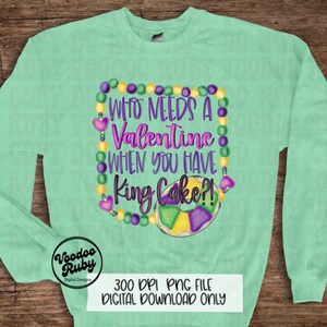 May include: A mint green crewneck sweatshirt featuring a graphic design with purple, yellow, and green Mardi Gras beads forming a border. The text reads "WHO NEEDS A Valentine WHEN YOU HAVE King Cake?!" above a colorful king cake illustration.