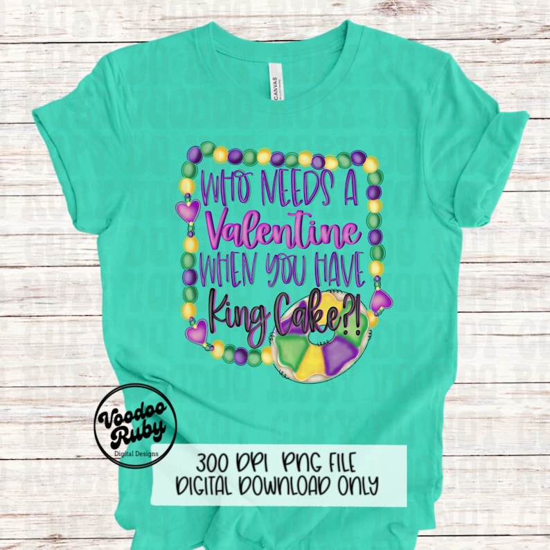 May include: A mint green t-shirt featuring a graphic design of purple, yellow, and green Mardi Gras beads forming a square frame. Inside the frame is the text "WHO NEEDS A VALENTINE WHEN YOU HAVE King Cake?!" with a colorful illustration of a king cake.