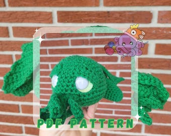 May include: Green crocheted amigurumi octopus plush toy with white eyes. The toy is being held in a hand with the text "PDF PATTERN" visible below.