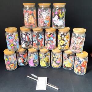 May include: A collection of 15 glass jars with cork lids and colorful cartoon character designs. The jars are arranged in a pyramid shape on a black surface.