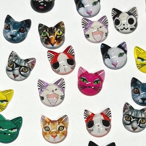 May include: Assortment of colorful cat-themed buttons with various designs and expressions. The buttons are made of plastic and have a glossy finish.