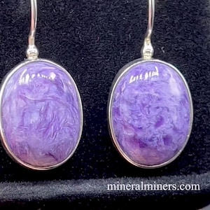Puede incluir: Un par de pendientes de plata con piedras de labradorita púrpura. Las piedras tienen un patrón de remolino y están engastadas en biseles ovalados.