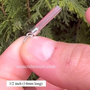May include: A close-up of a pink crystal pendant, 1/2 inch (14mm) long, with a silver bail. The pendant is being held by a hand, and the website "mineralminers.com" is visible in the background.