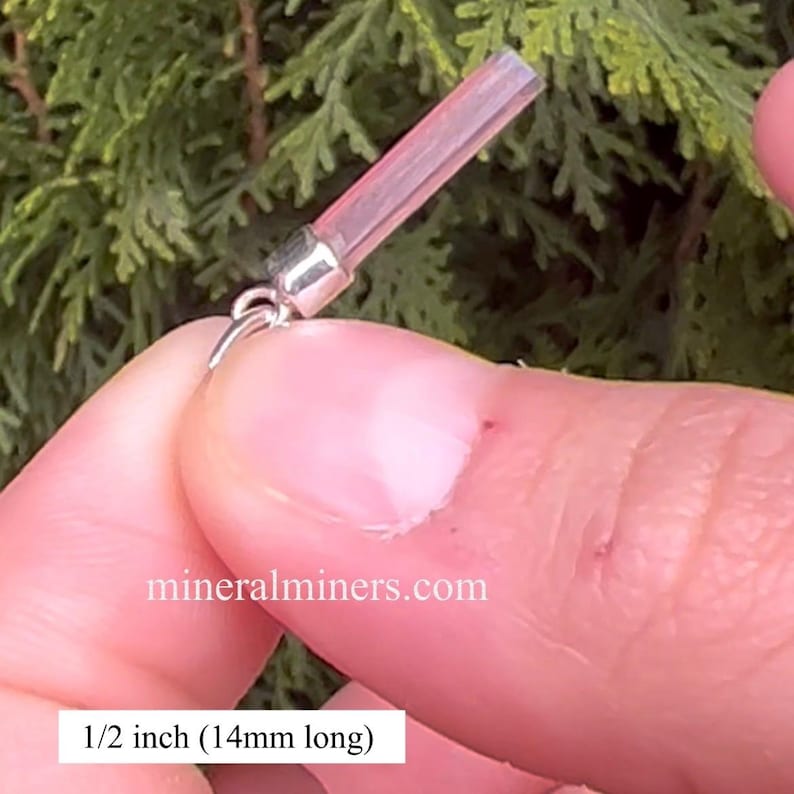 May include: A close-up of a pink crystal pendant, 1/2 inch (14mm) long, with a silver bail. The pendant is being held by a hand, and the website "mineralminers.com" is visible in the background.