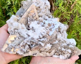 May include: A large, rough, gray and white crystal cluster with a silvery sheen. The crystal cluster is composed of many smaller crystals that are tightly packed together. The cluster is about the size of a person's hand.