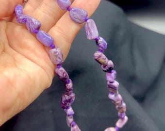 May include: A purple and white striped stone necklace with a silver clasp. The necklace is made of natural stones and is approximately 18 inches long.