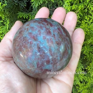 May include: A large, round, green and red sphere of polished gemstone. The sphere has a swirling pattern of green and red.