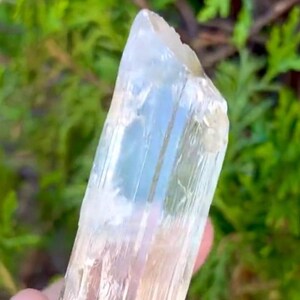 May include: A clear, translucent crystal point with a slightly yellow hue. The crystal has a smooth, polished surface and is approximately 3 inches long.