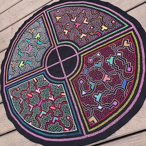May include: A circular black fabric piece featuring four distinct quadrants of intricate, colorful embroidery. Each section displays complex, maze-like geometric patterns in vibrant neon pink, blue, yellow, and green thread against the black base.