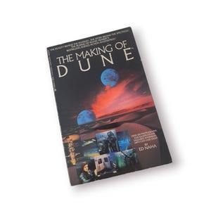 May include: A book cover with a black background and the title "The Making of Dune" in white text. The cover features a collage of images from the film, including a desert landscape, a spaceship, and a character in a costume.
