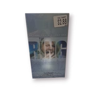 Peut inclure: Une cassette VHS du film d'horreur "The Ring" avec une femme qui crie sur la couverture. Le slogan dit "Avant de mourir, vous voyez... Tellement bien, c'est effrayant".