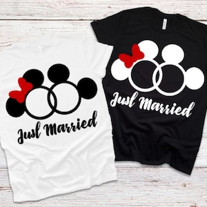 May include: Two white t-shirts with a black and white graphic of Mickey Mouse and Minnie Mouse with wedding rings. The text "Just Married" is printed on both shirts.