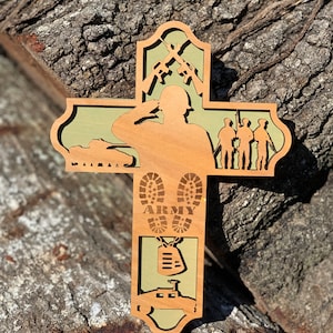 Może przedstawiać: Drewniany krzyż z zielonym tłem. Krzyż przedstawia sylwetkę żołnierza salutującego, czołg, buty z napisem "ARMY", identyfikator i jeepa.