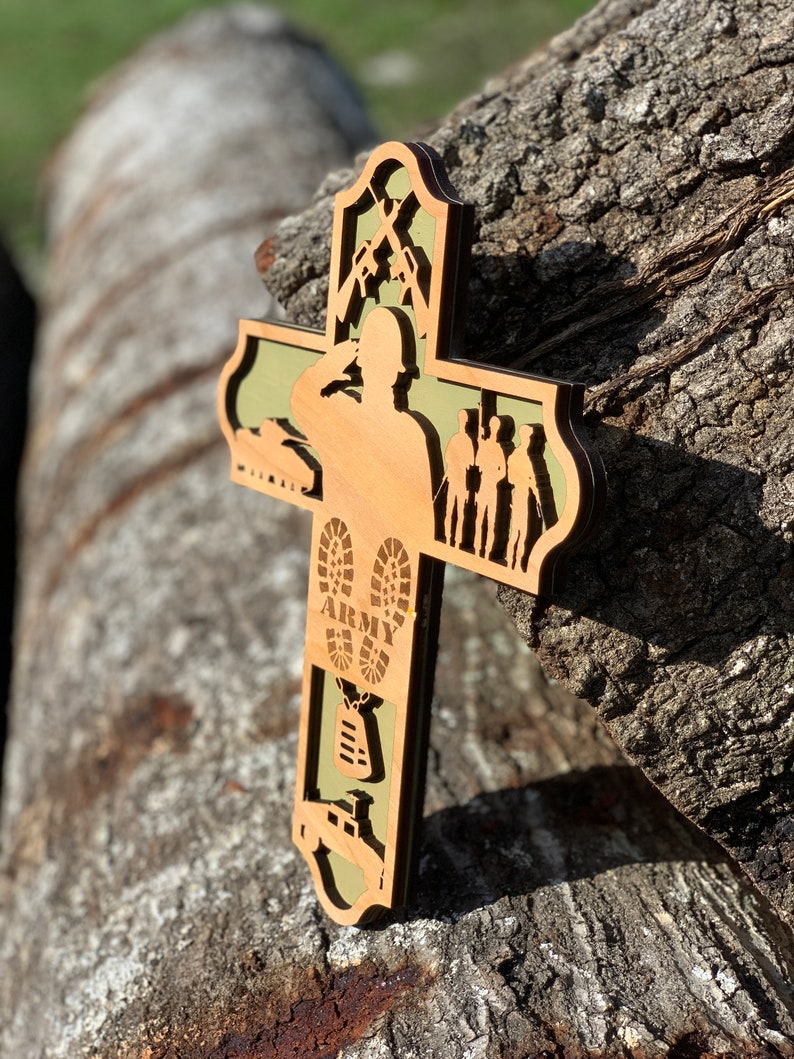 Może przedstawiać: Drewniany krzyż z zielonym tłem. Krzyż przedstawia sylwetkę żołnierza salutującego, czołg, buty z napisem "ARMY" i identyfikator.