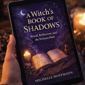 May include: A tablet displays the cover of "A Witch's Book of Shadows" by Michelle Hoffmann. The cover features a dark purple background with a crescent moon and stars. An open book, a candle, and a feather are also visible.