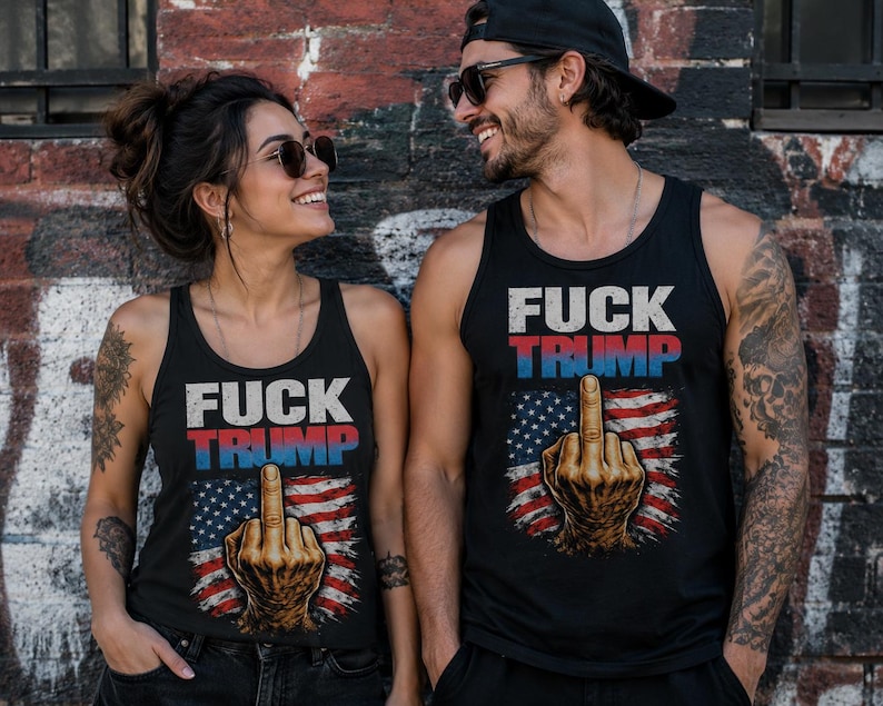 K&ouml;nnte beinhalten: Schwarze Tanktops mit dem Text "FUCK TRUMP" in wei&szlig;en und roten Buchstaben &uuml;ber einer Grafik der amerikanischen Flagge und einer Hand, die den Mittelfinger zeigt. Die Tanktops werden von zwei Personen getragen.