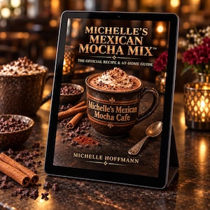 Puede incluir: Una tableta digital que muestra la portada del libro Michelle's Mexican Mocha Mix: The Official Recipe & At-Home Guide de Michelle Hoffmann. La portada presenta una taza de cerámica oscura llena de moca, nata montada y virutas.