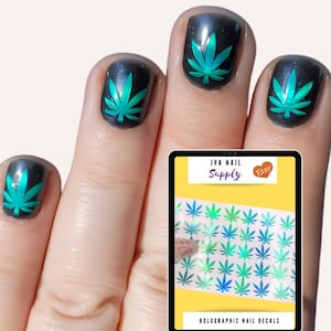 May include: Holographic nail decals featuring a green marijuana leaf design. The decals are shown on a hand with a clear background. The image also includes a product label that reads "IVA Nail Supply Etsy" and "Holographic Nail Decals".