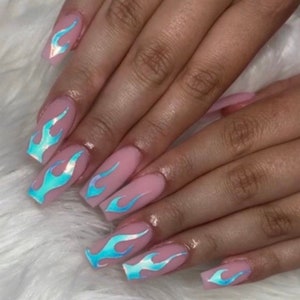 May include: Close-up of long, light pink nails with blue iridescent flame designs. The nails are long and square-shaped.