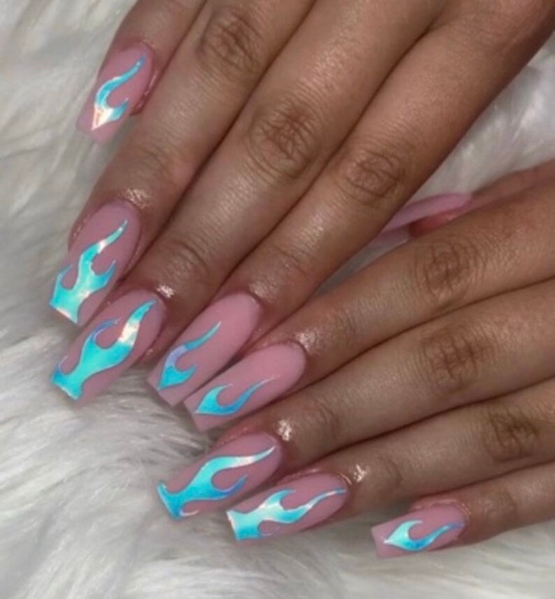 May include: Close-up of long, light pink nails with blue iridescent flame designs. The nails are long and square-shaped.