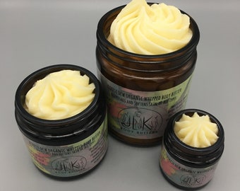 May include: Three glass jars of whipped body butter with a yellow swirl on top. The jars are labeled "Forest Dew Organic Whipped Body Butter" and "Nourishes and Softens Skin of All Types".