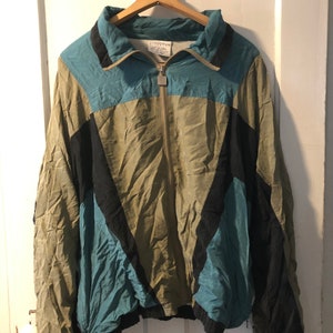 May include: A green, blue and black windbreaker jacket with a zip closure. The jacket has a stand-up collar and a drawstring at the waist.