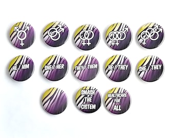 May include: A collection of round, colorful buttons with various designs and text. Some buttons feature gender symbols, while others display pronouns like "He/Him" and "She/Her." Additional buttons have the phrases "Smash the Cistem" and "Healthcare for All."