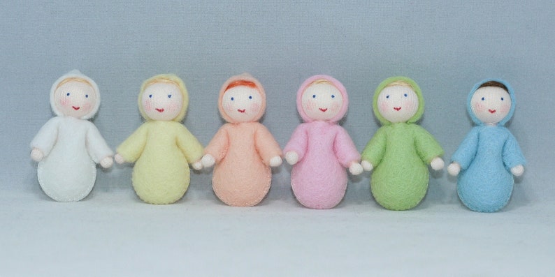 Puede incluir: Seis mu&ntilde;ecas de fieltro de diferentes colores, incluyendo blanco, amarillo, rosa, melocot&oacute;n, verde y azul. Cada mu&ntilde;eca tiene una cara simple con ojos bordados y una sonrisa.
