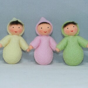 Puede incluir: Cinco mu&ntilde;ecas de beb&eacute; de fieltro en diferentes colores, cada una con un mono con capucha. Las mu&ntilde;ecas sonr&iacute;en y tienen el pelo casta&ntilde;o.