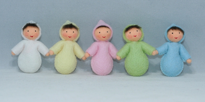 Puede incluir: Cinco mu&ntilde;ecas de beb&eacute; de fieltro en diferentes colores, cada una con un mono con capucha. Las mu&ntilde;ecas sonr&iacute;en y tienen el pelo casta&ntilde;o.