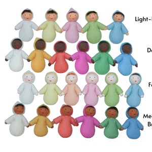 Puede incluir: Un conjunto de 18 mu&ntilde;ecas de fieltro en varios tonos de piel, cada una con un atuendo con capucha de un color diferente. Las mu&ntilde;ecas est&aacute;n dispuestas en c&iacute;rculo, con los colores de sus atuendos formando un arco&iacute;ris. Las mu&ntilde;ecas est&aacute;n hechas de fieltro suave y natural y son perfectas para juegos imaginativos.
