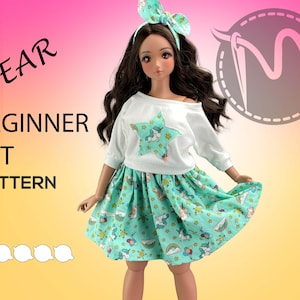 May include: A doll wearing a white shirt with a star and unicorn print and a green skirt with a unicorn and rainbow print. The text "PEAR BEGINNER SET PATTERN" is on the image.